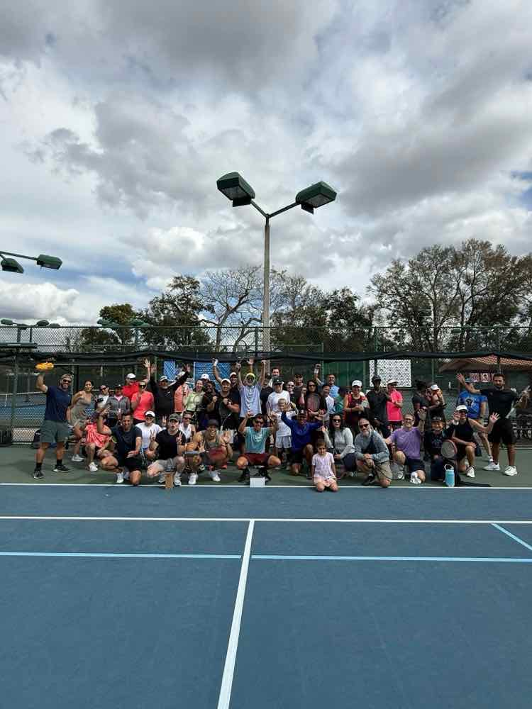 A big group of players posing on court on a bright day
